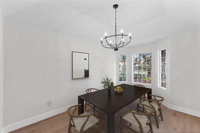 dining space featuring light wood finished floors, an inviting chandelier, and baseboards