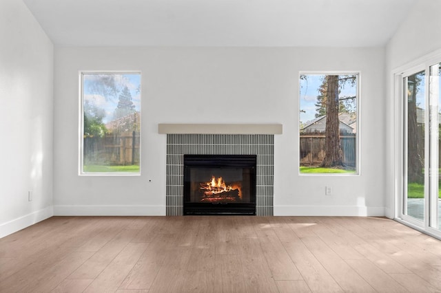 unfurnished living room with baseboards, wood finished floors, and a fireplace