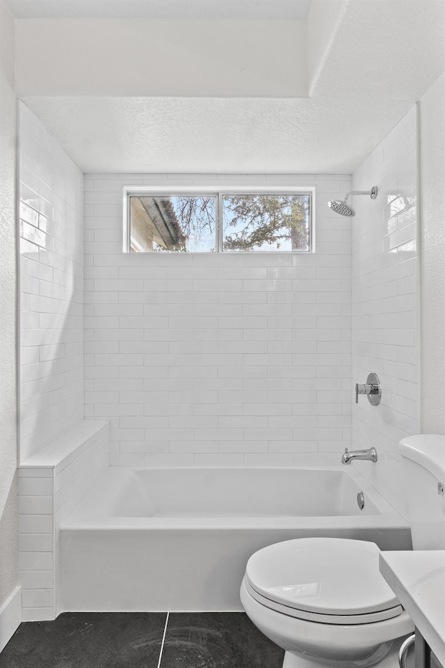 full bathroom with tile patterned flooring, a textured ceiling, toilet, and shower / tub combination