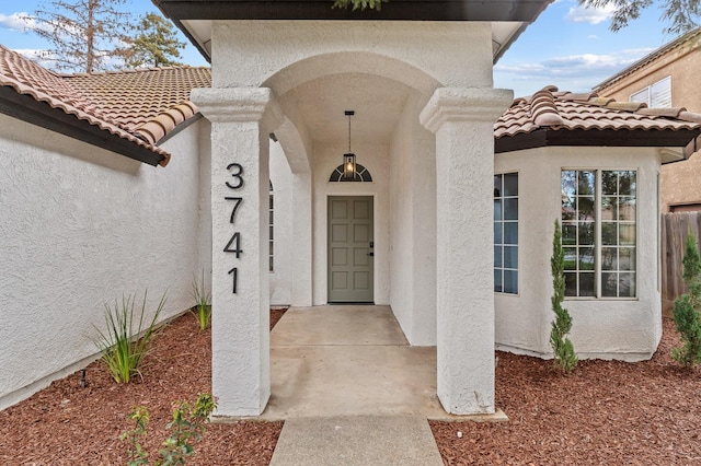 view of exterior entry with stucco siding and a tile roof