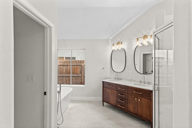 bathroom with double vanity, a freestanding tub, a shower with door, and a sink