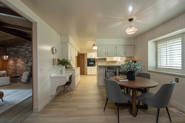 dining space with light wood finished floors, visible vents, and baseboards