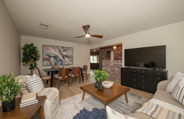 living area with wood finished floors, a ceiling fan, visible vents, and a textured ceiling