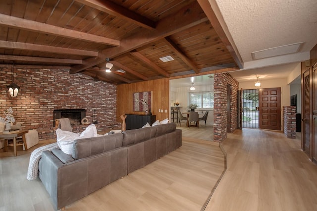 living area with a brick fireplace, vaulted ceiling with beams, wood ceiling, and light wood finished floors