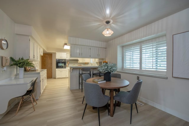 dining space featuring light wood-style floors and baseboards