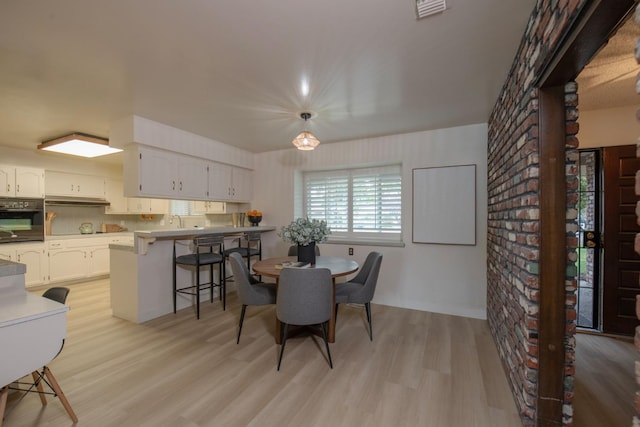 dining area featuring light wood-style flooring and visible vents