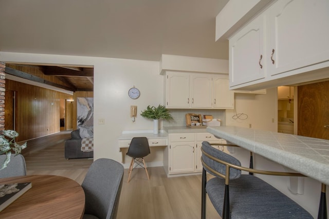 kitchen featuring backsplash, vaulted ceiling with beams, wooden ceiling, light wood-style floors, and white cabinets