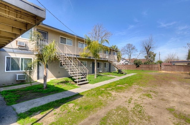 view of yard featuring an AC wall unit, stairs, and fence