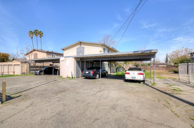 view of front of house with covered parking, stucco siding, and fence