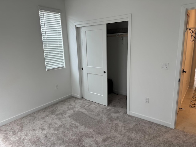 unfurnished bedroom with multiple windows, carpet flooring, baseboards, and a closet