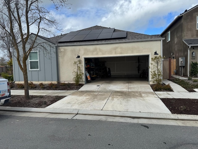 view of home's exterior with driveway, roof with shingles, solar panels, an attached garage, and stucco siding