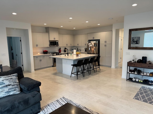 kitchen with a breakfast bar area, recessed lighting, stainless steel appliances, light countertops, and open floor plan