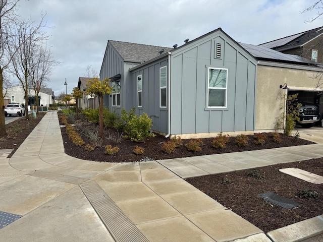 view of side of home featuring board and batten siding and a shingled roof