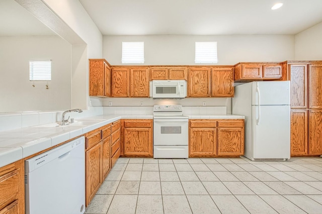 kitchen with white appliances, tile countertops, light tile patterned floors, a healthy amount of sunlight, and a sink