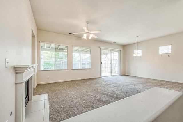 carpeted living area featuring a wealth of natural light, visible vents, and ceiling fan with notable chandelier