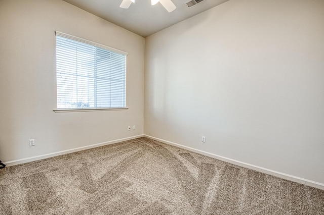 empty room with visible vents, carpet flooring, a ceiling fan, and baseboards