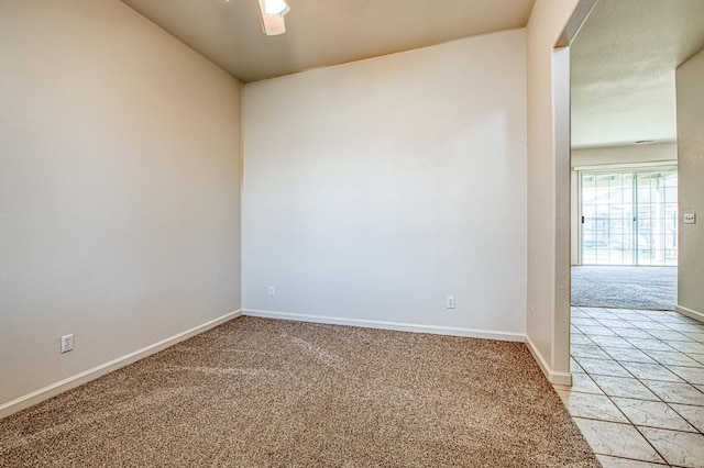 empty room with baseboards, light carpet, and a ceiling fan