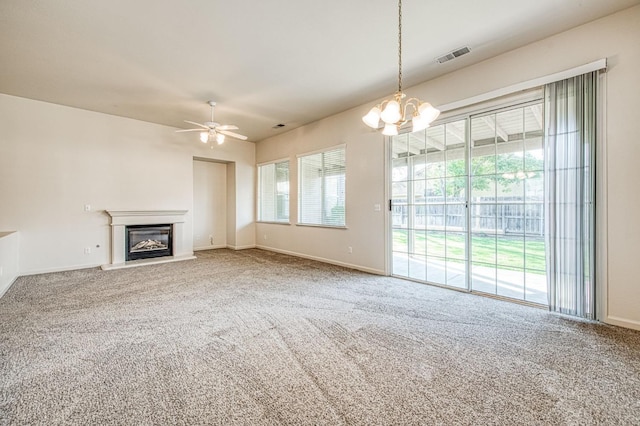 unfurnished living room with visible vents, a glass covered fireplace, carpet flooring, and ceiling fan with notable chandelier