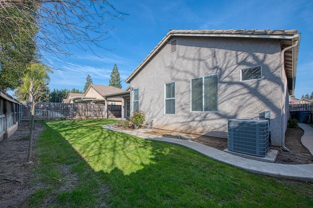 back of property with central AC unit, a lawn, a fenced backyard, and stucco siding