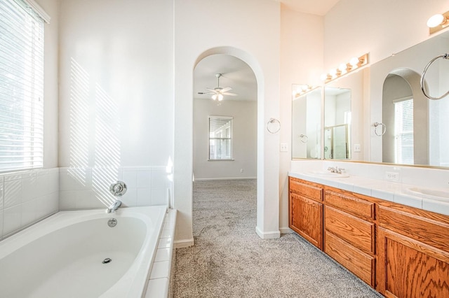 full bathroom featuring double vanity, a healthy amount of sunlight, ceiling fan, and a bath