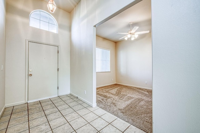 entrance foyer featuring baseboards, light carpet, a healthy amount of sunlight, and a ceiling fan