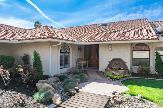 property entrance featuring a tile roof and stucco siding