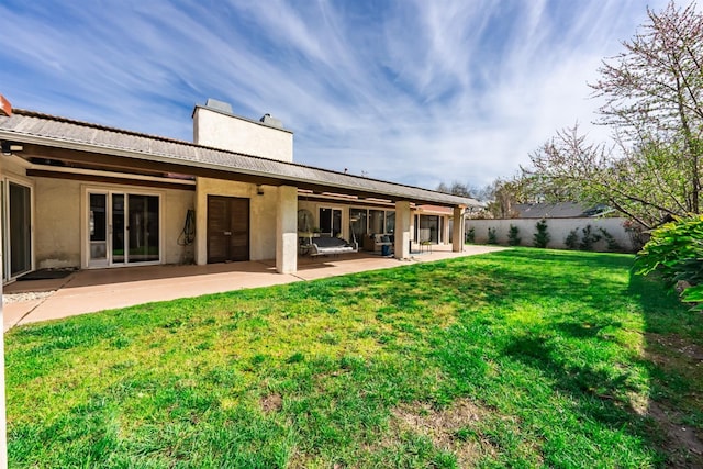 rear view of property with fence, a lawn, stucco siding, a chimney, and a patio