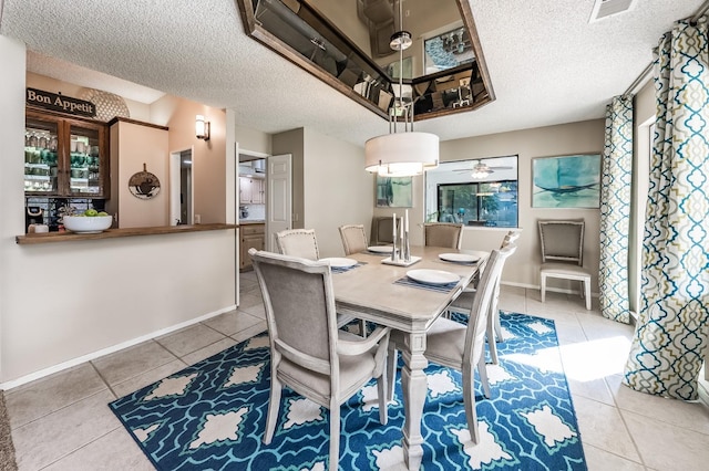 tiled dining area featuring baseboards, visible vents, a textured ceiling, and a ceiling fan