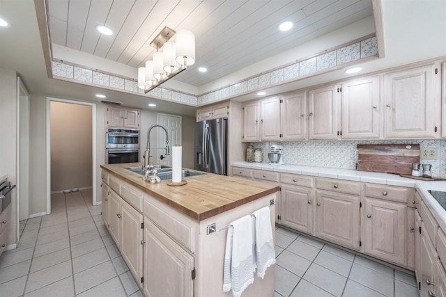 kitchen featuring a sink, tasteful backsplash, appliances with stainless steel finishes, and an island with sink