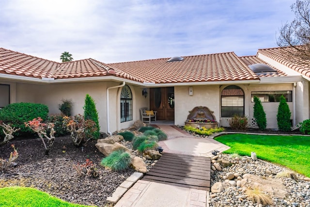 view of front of home featuring stucco siding, a front yard, and a tiled roof