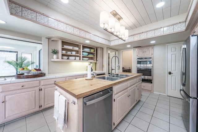 kitchen featuring open shelves, light tile patterned flooring, a kitchen island with sink, a sink, and appliances with stainless steel finishes