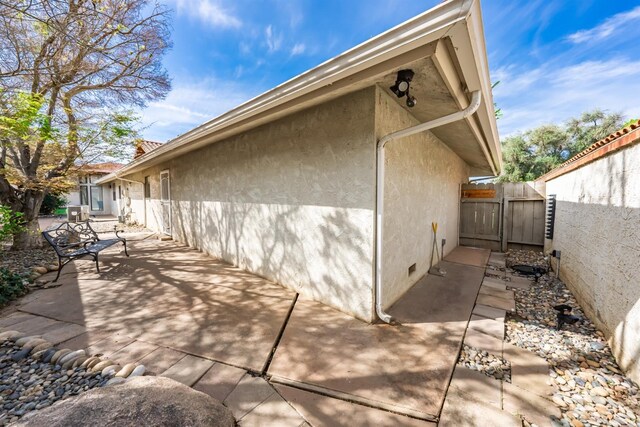 view of property exterior with a patio, fence, crawl space, and stucco siding