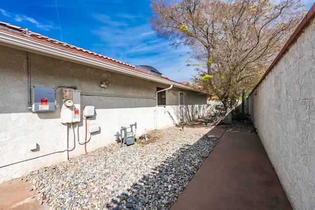 view of side of property featuring stucco siding and fence