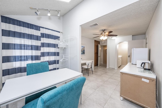 interior space with tile patterned flooring, visible vents, curtained shower, a textured ceiling, and a ceiling fan