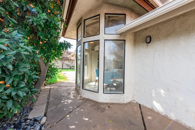 entrance to property with stucco siding and a patio