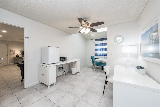 home office featuring a textured ceiling, light tile patterned floors, baseboards, and ceiling fan