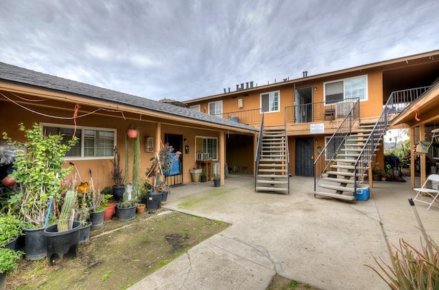 rear view of property with stairs, a patio, cooling unit, and stucco siding