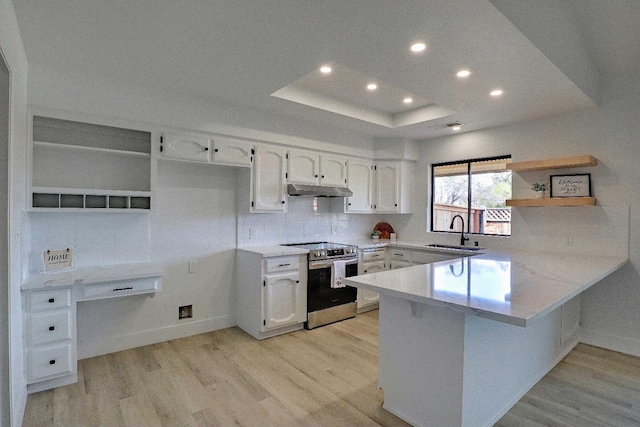 kitchen with open shelves, a tray ceiling, a sink, stainless steel range with electric cooktop, and a peninsula