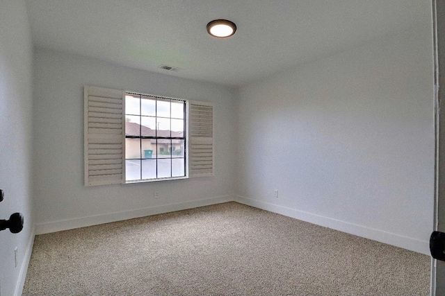 carpeted spare room featuring visible vents and baseboards