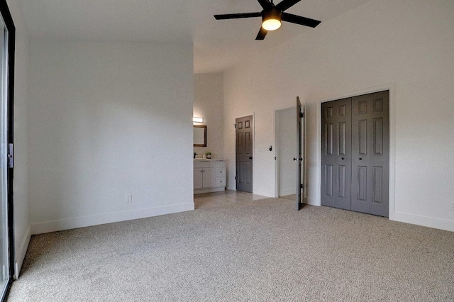 unfurnished bedroom featuring connected bathroom, baseboards, ceiling fan, light carpet, and high vaulted ceiling