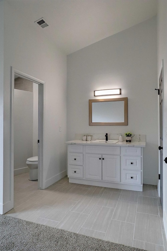 bathroom with vanity, toilet, baseboards, and visible vents