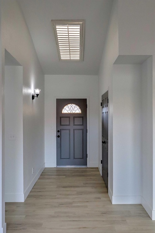 foyer with light wood-type flooring, baseboards, and visible vents