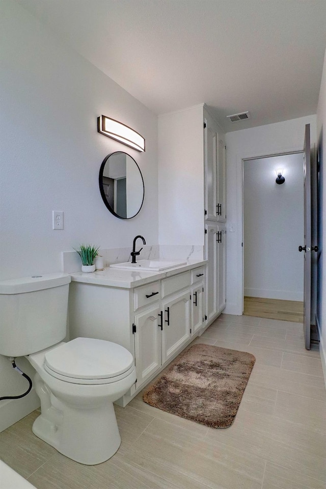 bathroom featuring tile patterned flooring, visible vents, baseboards, toilet, and vanity