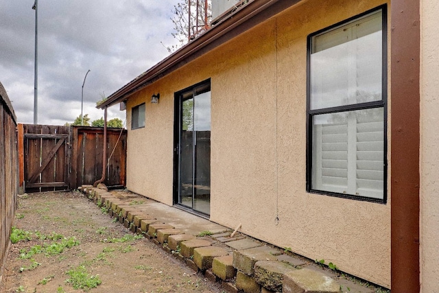 view of home's exterior featuring a gate, stucco siding, and fence