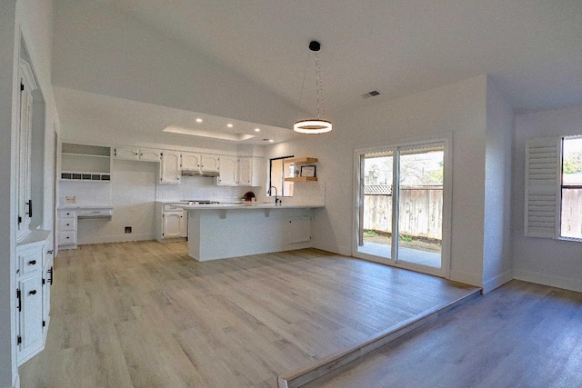 kitchen with light wood-type flooring, visible vents, a peninsula, and a healthy amount of sunlight