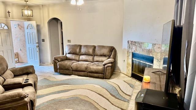 living room with ceiling fan, carpet, arched walkways, and a premium fireplace