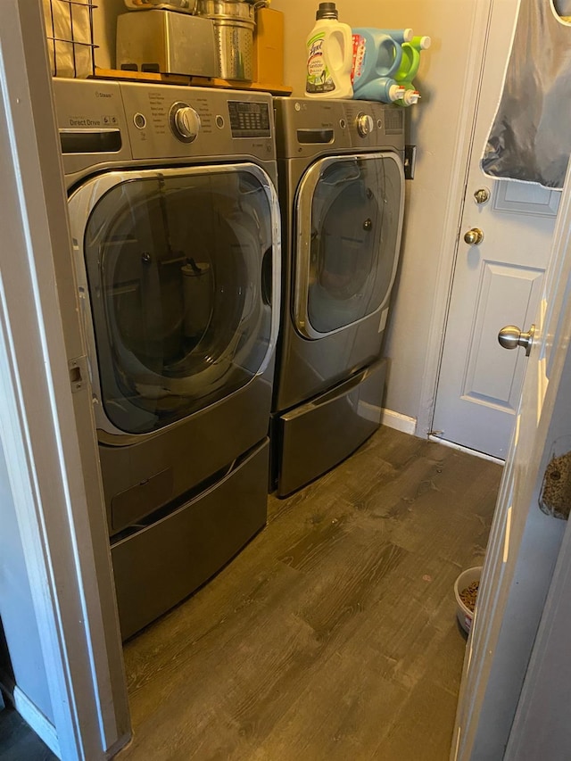 clothes washing area with washer and clothes dryer, laundry area, baseboards, and wood finished floors