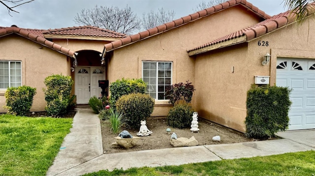 doorway to property featuring a tiled roof, a garage, and stucco siding