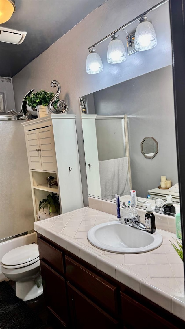 bathroom with enclosed tub / shower combo, toilet, and vanity