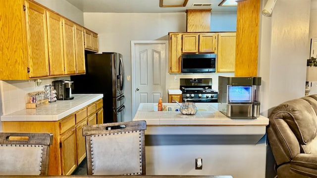 kitchen with tile countertops, visible vents, backsplash, and stainless steel appliances